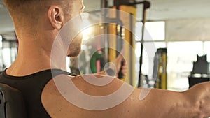 Sporty male with developed muscles doing chest fly exercise at fast pace in gym