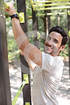 sporty man doing chin-ups on horizontal bars