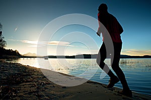 Sporty Man doing Morning Jogging on Sea Beach at Bright Sunrise Silhouettes