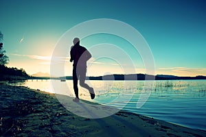 Sporty Man doing Morning Jogging on Sea Beach at Bright Sunrise Silhouettes