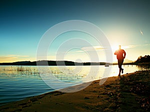 Sporty Man doing Morning Jogging on Sea Beach at Bright Sunrise Silhouettes