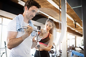 Sporty man doing weight exercises with assistance of her personal trainer