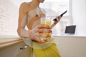 Sporty man drinking orange juice using mobile app