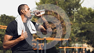 Sporty man drinking water after workout outside
