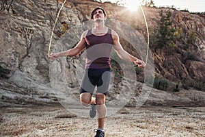 Sporty man jumping rope outdoors