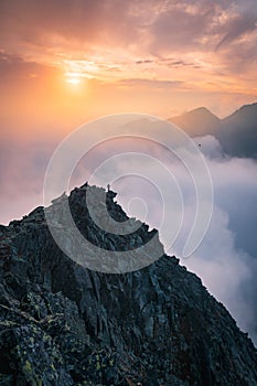 Sporty man on the mountain peak looking on mountain valley with sunbeams at colorful sunset in autumn in Europe. Landscape with