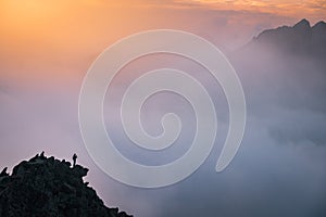 Sporty man on the mountain peak looking on mountain valley with sunbeams at colorful sunset in autumn in Europe. Landscape with