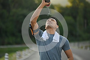 Sporty man pouring water over his face to refresh after after training hard outdoor