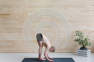 Sporty man practices yoga handstand asana Adho Mukha Vrikshasana at the yoga studio