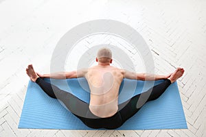 Sporty man practicing yoga. Asana Kurmasana. Tortoise pose. Tortoise posture.