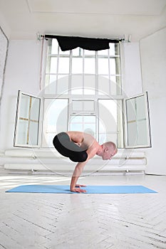 Sporty man practicing yoga. Handstand Urdhva Kukkutasana. Upward