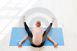 Sporty man practicing yoga. Kurmasana. Tortoise pose. Tortoise posture