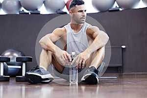 Sporty man resting, having break drinking water after doing exercise