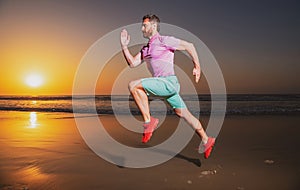 Sporty man runner running in summer sea beach. Attractive fit man run on sunset light, workout outdoors, jogging with