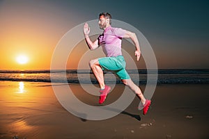 Sporty man runner running in summer sea beach. Attractive fit man run on sunset light, workout outdoors, jogging with