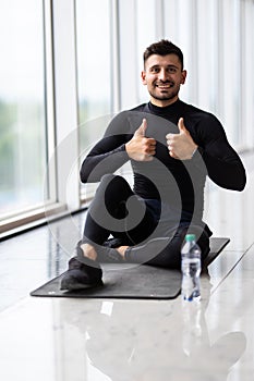 Sporty man with thumbs up resting, having break drinking water after doing exercise