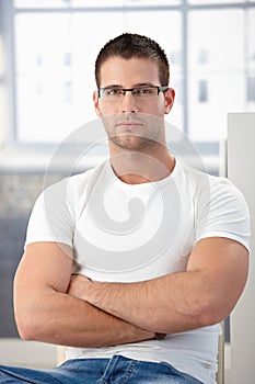 Sporty man wearing glasses sitting arms crossed