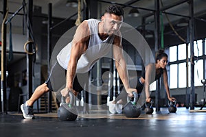 Sporty man and woman doing push-up in a gym