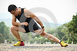 Sporty mature Asian man in sportswear stretching his legs, side lunges, warming up