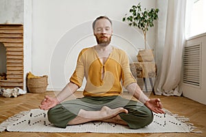 Sporty mindful man meditating alone at home apartment