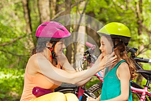 Sporty mother helping her daughter to clasp helmet