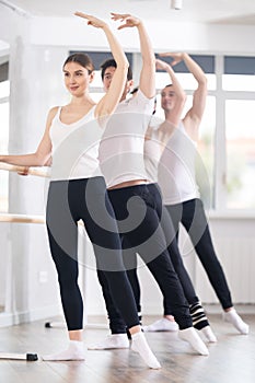 Woman performing battement tendu at group barre fitness session photo