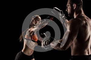 Sporty muscular young man and woman boxing together