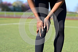 Sporty muscular young woman clutching her knee