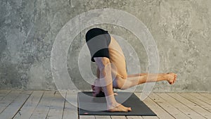 Sporty muscular young yogi man doing Wide-Legged Forward Bend, Prasarita Padottanasana posture Dandayamana Bibhaktapada