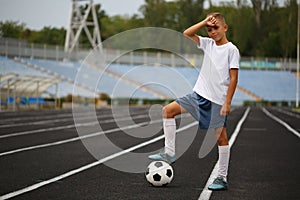 A sporty player with a football ball under his foot on a green grass on a stadium background. Hobby, activities concept.