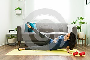 Sporty pregnant woman stretching her legs at home