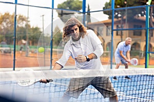 Sporty resolved man playing padel on open court