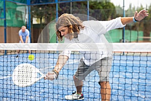 Sporty resolved man playing padel on open court