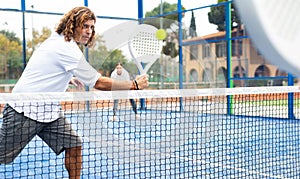 Sporty resolved man playing padel on open court