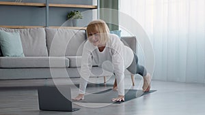Sporty Senior Female At Laptop Standing In Plank At Home