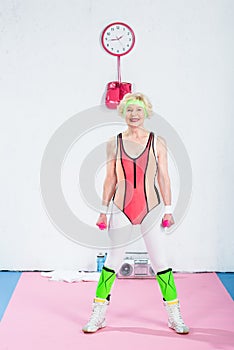 sporty senior lady holding dumbbells and smiling