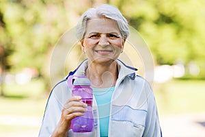 Sporty senior woman with bottle of water at park