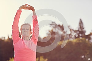 Sporty senior woman doing exercise warm-up stretches outdoors