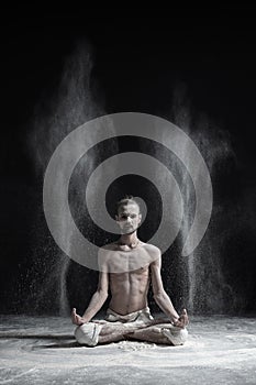 Sporty serene young man meditating sitting in cross-legged yoga lotus pose, Padmasana with palms in mudra