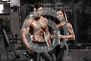 Sporty couple showing muscle and workout in gym. Muscular man and woman