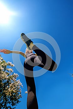 Sporty sexy girl jumping over camera in the summer sun under the sky, view from below, copy space