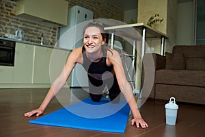 Sporty skinny girl in a black workout tight suit is doing knee push-ups at home