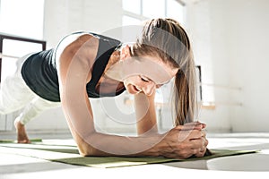 Sporty smiling female athlete doing abs exercise in white sunny gym