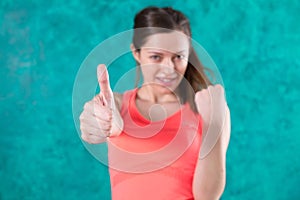 Sporty smiling girl shows gesture thumb up