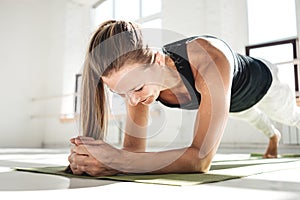 Sporty strong woman doing crossfit workout on yoga mat in sunny gum