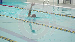 Sporty swimmer hardly working out in indoor empty pool swimming across track. Healthy lifestyle. Sports and recreation.