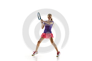 Sporty teenage tennis player in uniform ready to hit two-handed backhand stroke in motion against white studio