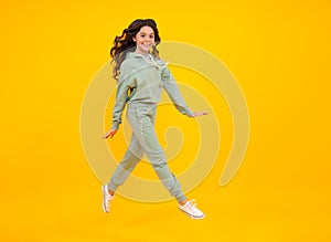 Sporty teenager child wearing a casual sport look. Cute teen girl in sports suit posing over yellow background.