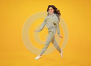 Sporty teenager child wearing a casual sport look. Cute teen girl in sports suit posing over yellow background.