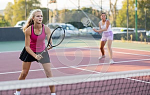 Sporty teenager girl player hitting ball with racket during friendly doubles couple match